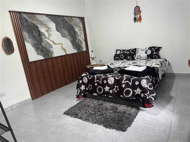 eco-hotel-gaia-13 - Alquiler de Fincas en el Quindio, Hoteles en el Eje Cafetero Double bed with black-and-white starry bedding, two folded towels on top, a gray shag rug, and a marble-pattern headboard panel; a dreamcatcher hangs from the ceiling.