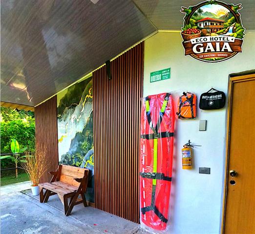 eco-hotel-gaia-6 - Alquiler de Fincas en el Quindio, Hoteles en el Eje Cafetero Entrance to Eco Hotel Gaia with a wooden bench, vertical slats, and safety gear mounted near the door.