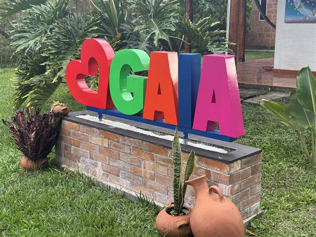 eco-hotel-gaia-7 - Alquiler de Fincas en el Quindio, Hoteles en el Eje Cafetero Colorful 3D letters spelling GAGA with a red heart, placed on a brick planter in a garden with plants and a clay pot nearby.